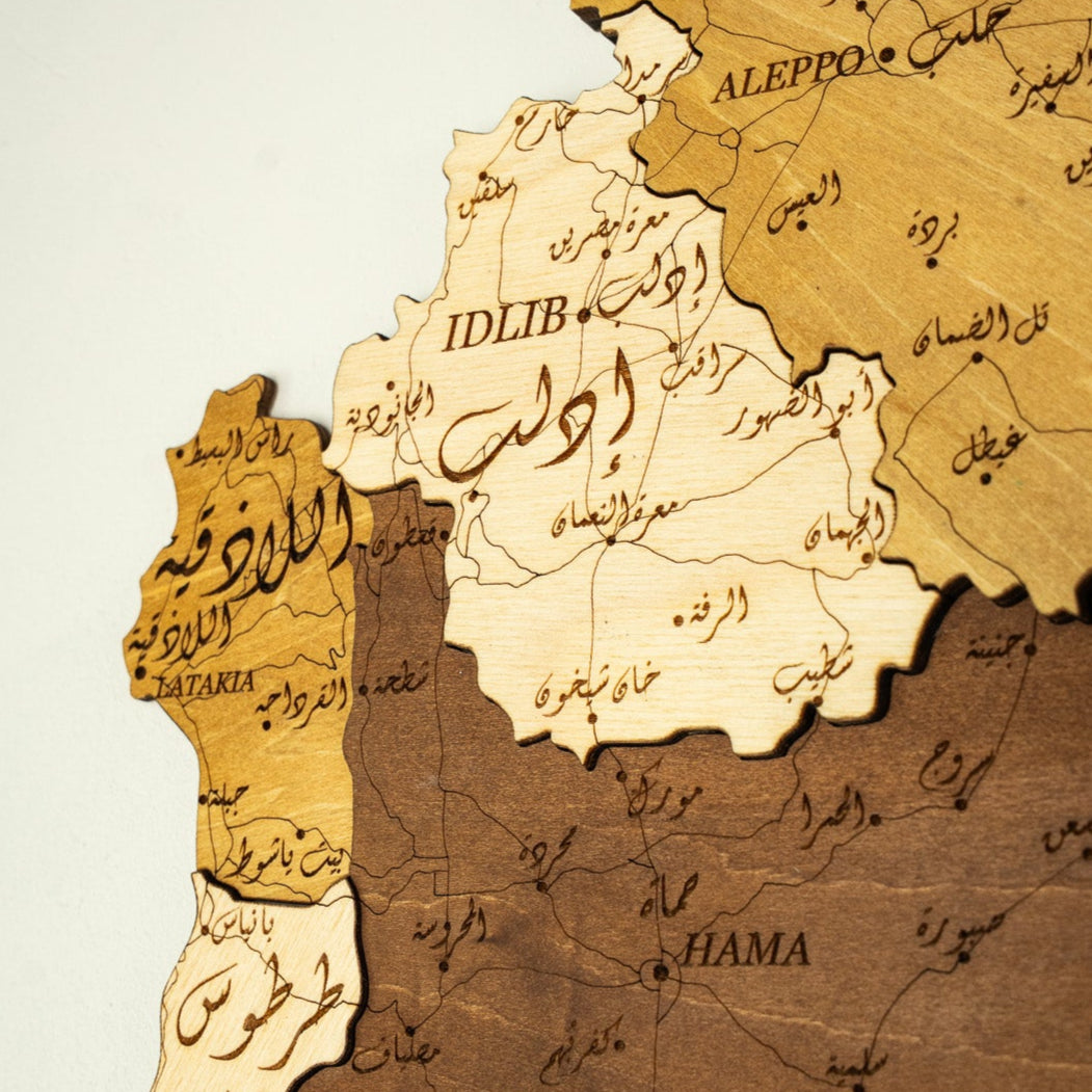 Wooden map of Syria with Arabic text on a white background