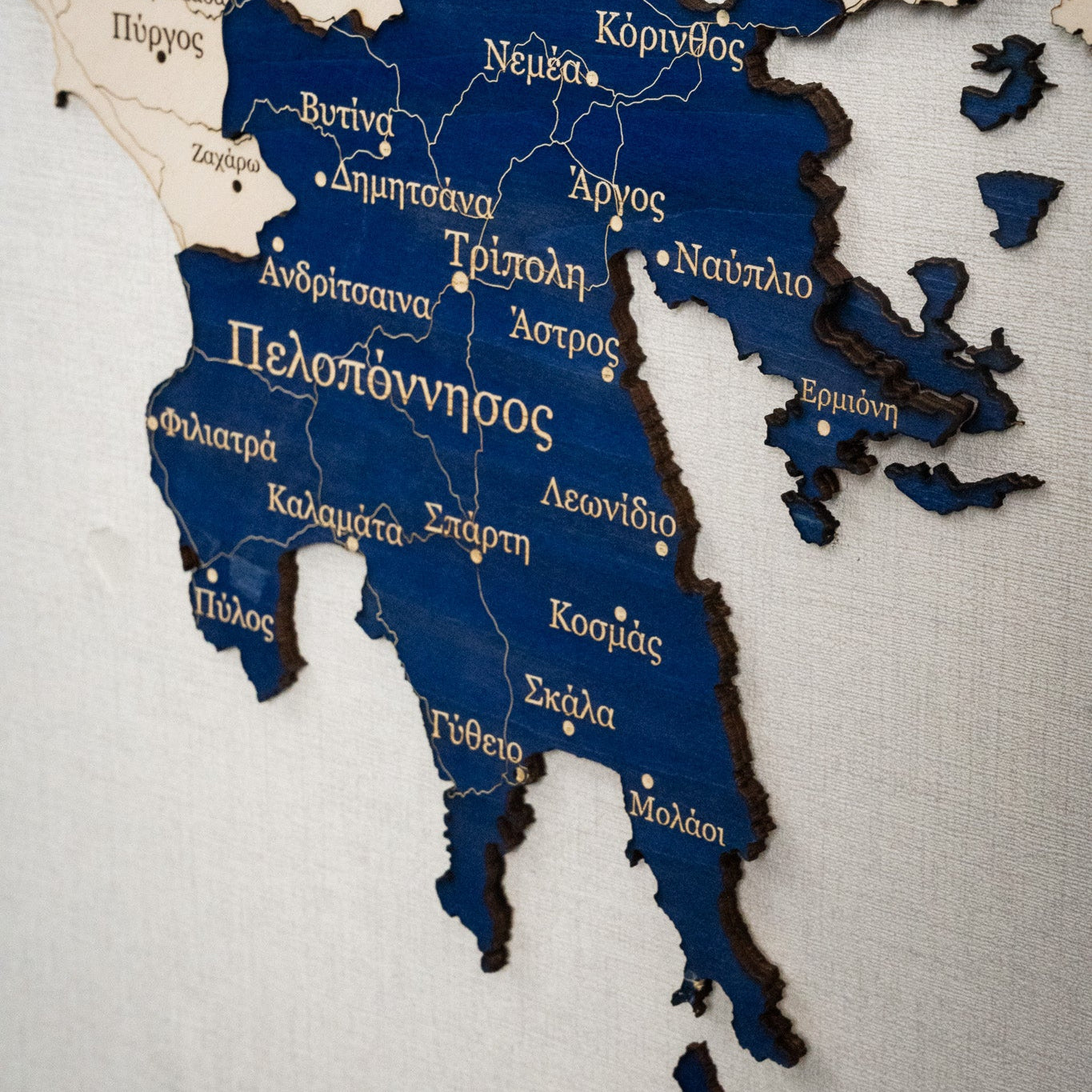 Wooden map of Greece with Greek text on a white background
