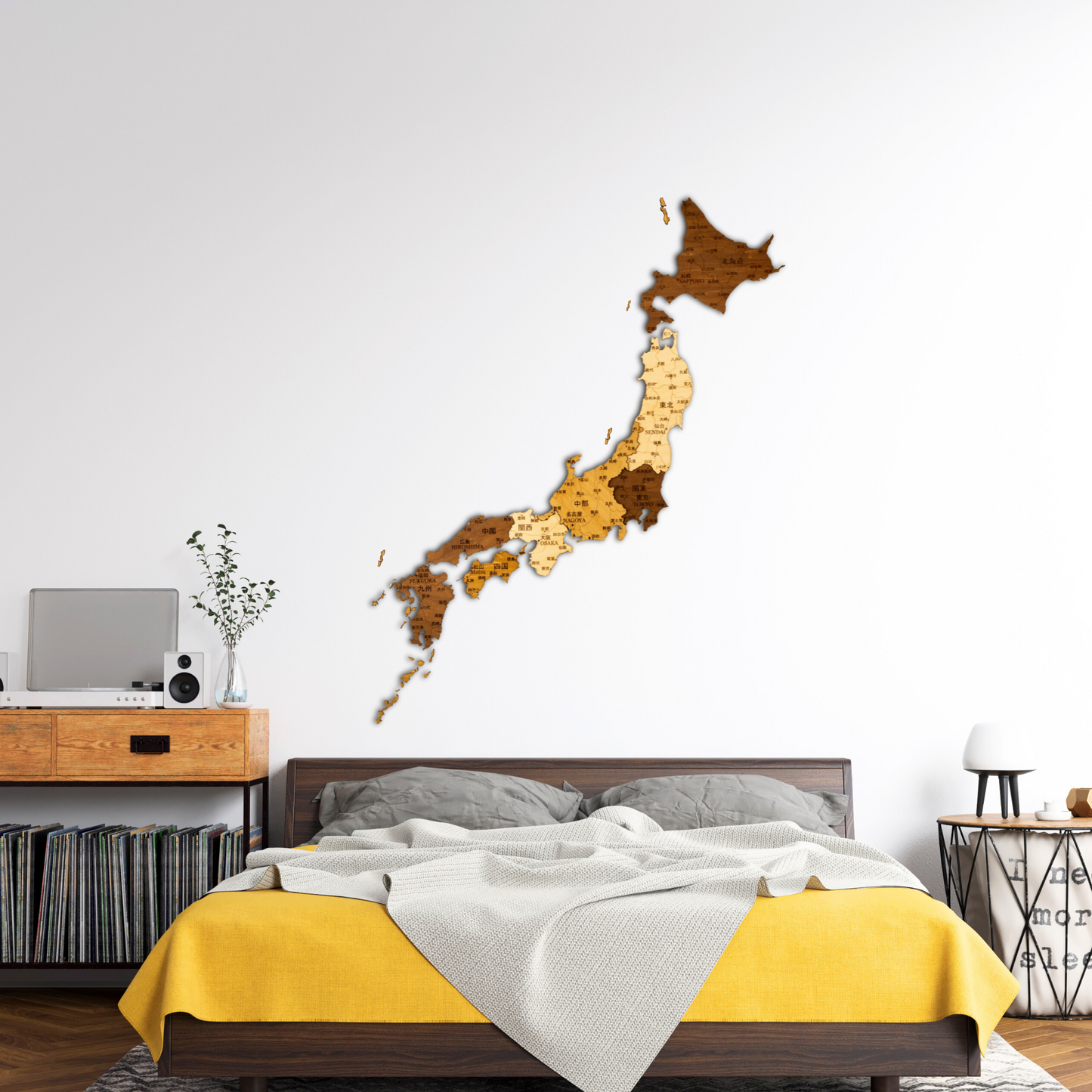 Wooden map of Japan on a wall above a bed with yellow and gray bedding.