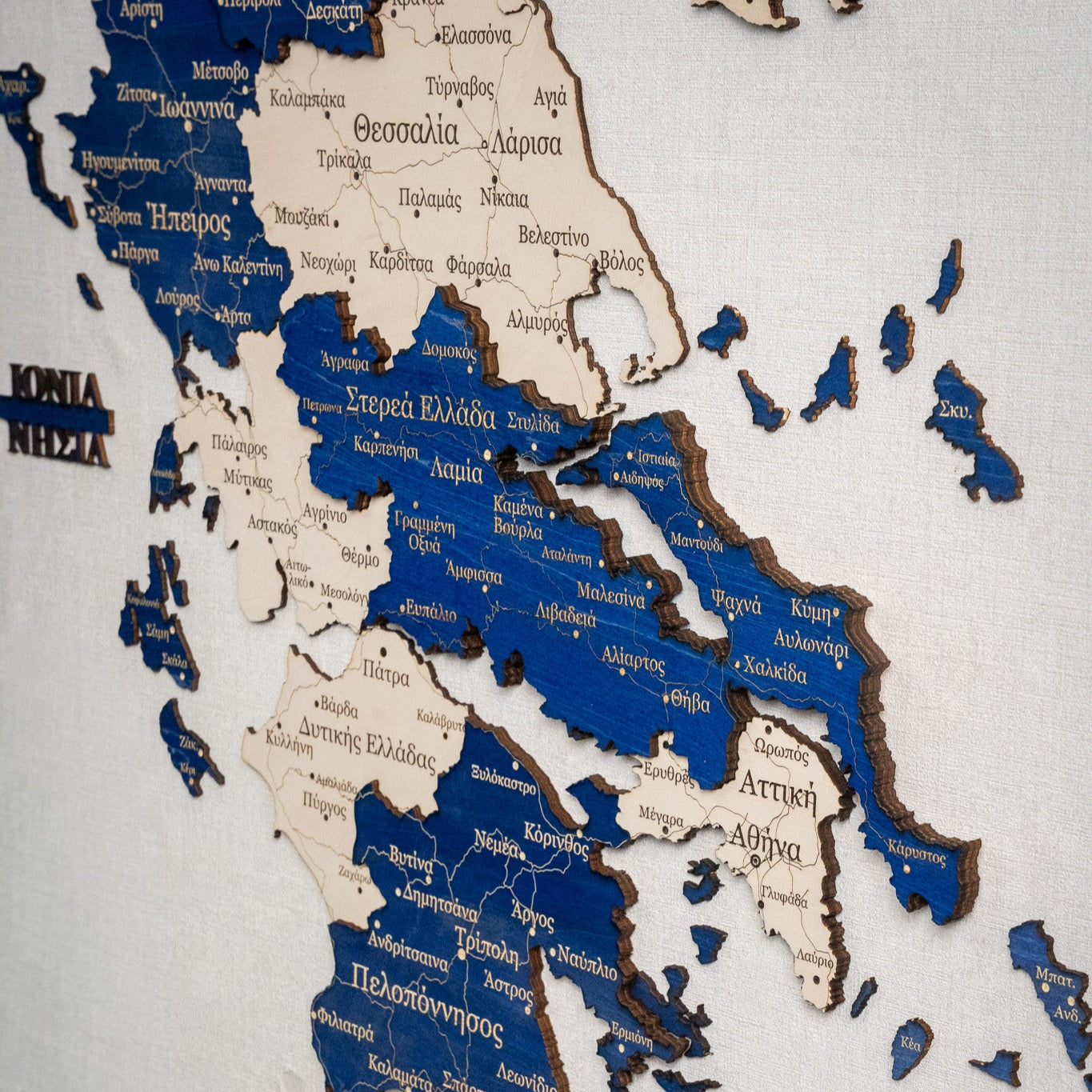 Wooden map of Greece with blue and brown colors on a white background
