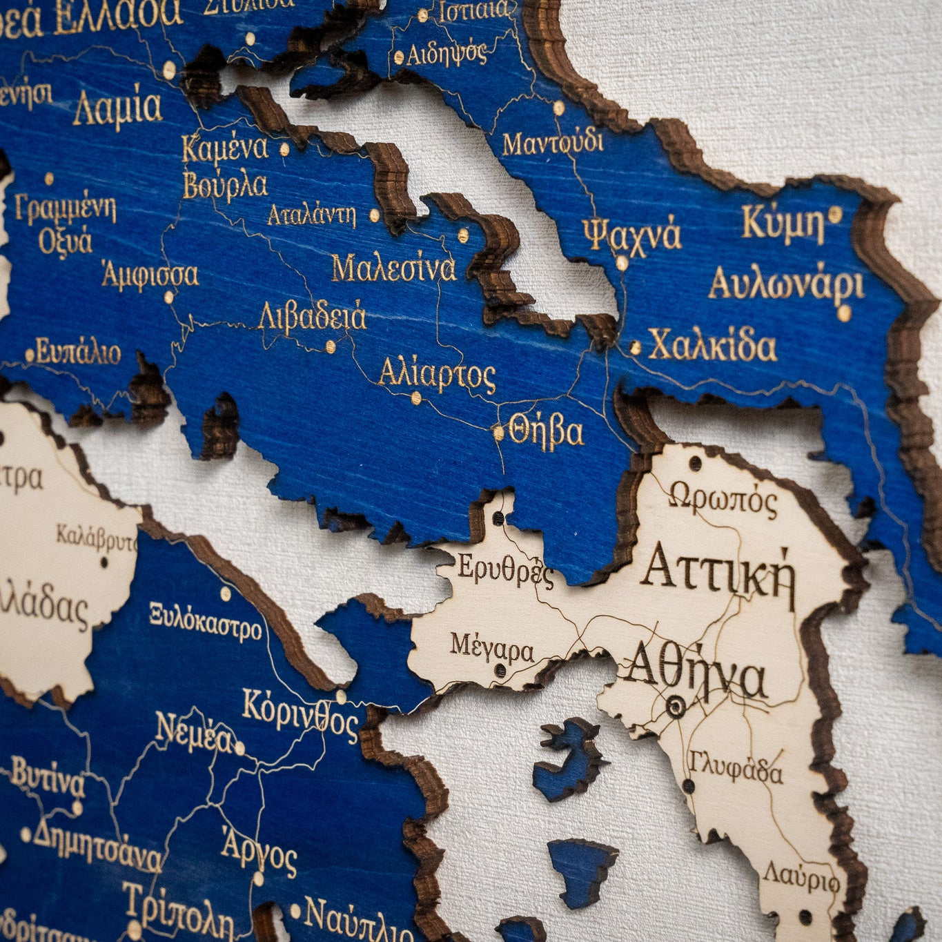 Wooden map of Greece with regions labeled in blue and brown.