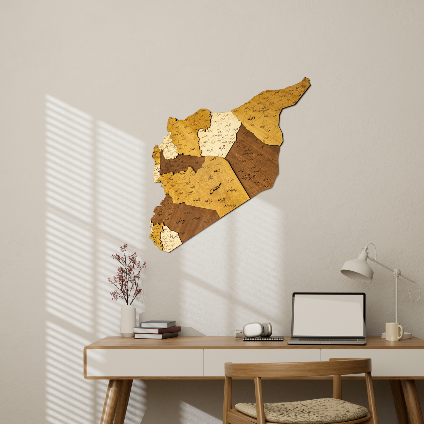 Wooden wall art of Syria map on a beige wall above a desk with a laptop.