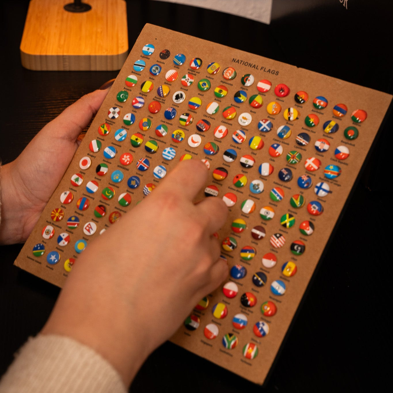 Hand interacting with a card of international flag push pins.