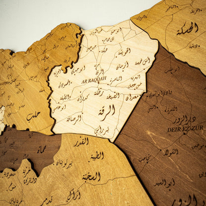 Wooden map of Syria with Arabic text on a light gray background