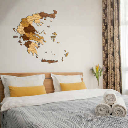 Bedroom with wooden wall art of a Greece map in Greek language, bed with white and yellow bedding, and side table with flowers.