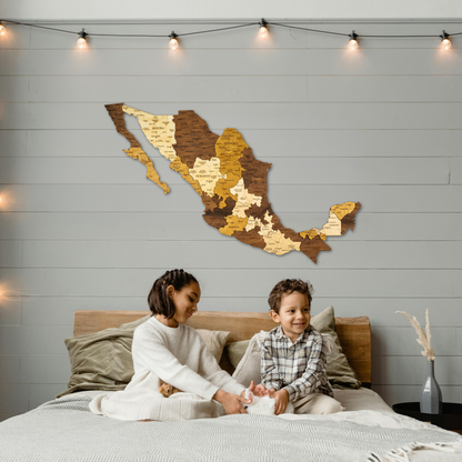 Two children sitting on a bed with a wooden map of Mexico on the wall.