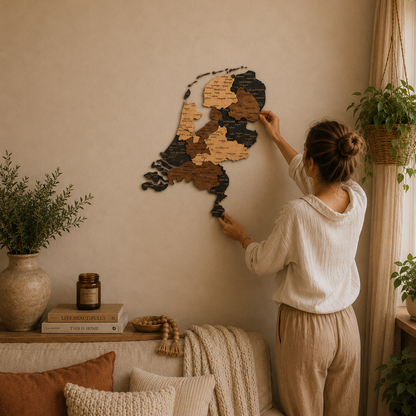 Woman arranging wooden puzzle pieces of wooden map of Netherlands on a wall in a cozy living room.