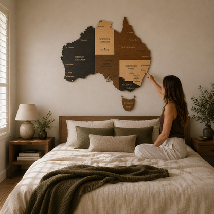 Woman pointing at a wall-mounted map of Australia in a bedroom.