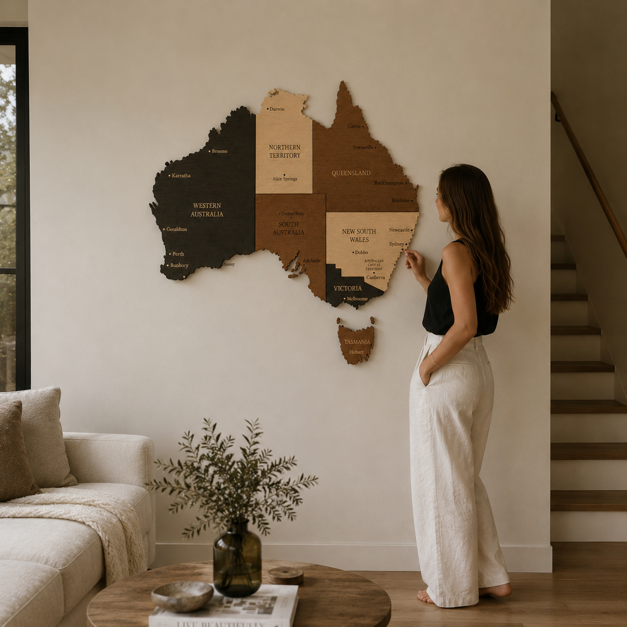 Woman standing in a living room looking at a large wooden map of Australia on the wall.