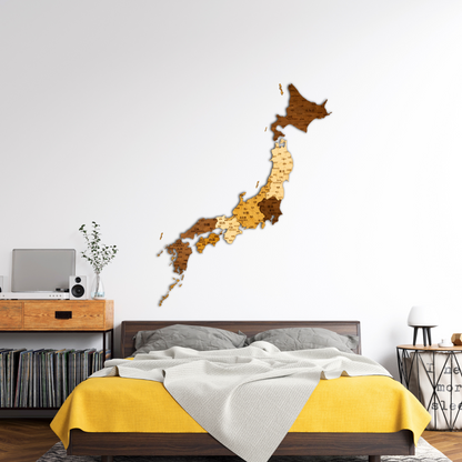 Wooden map of Japan on a wall above a bed with yellow and gray bedding.