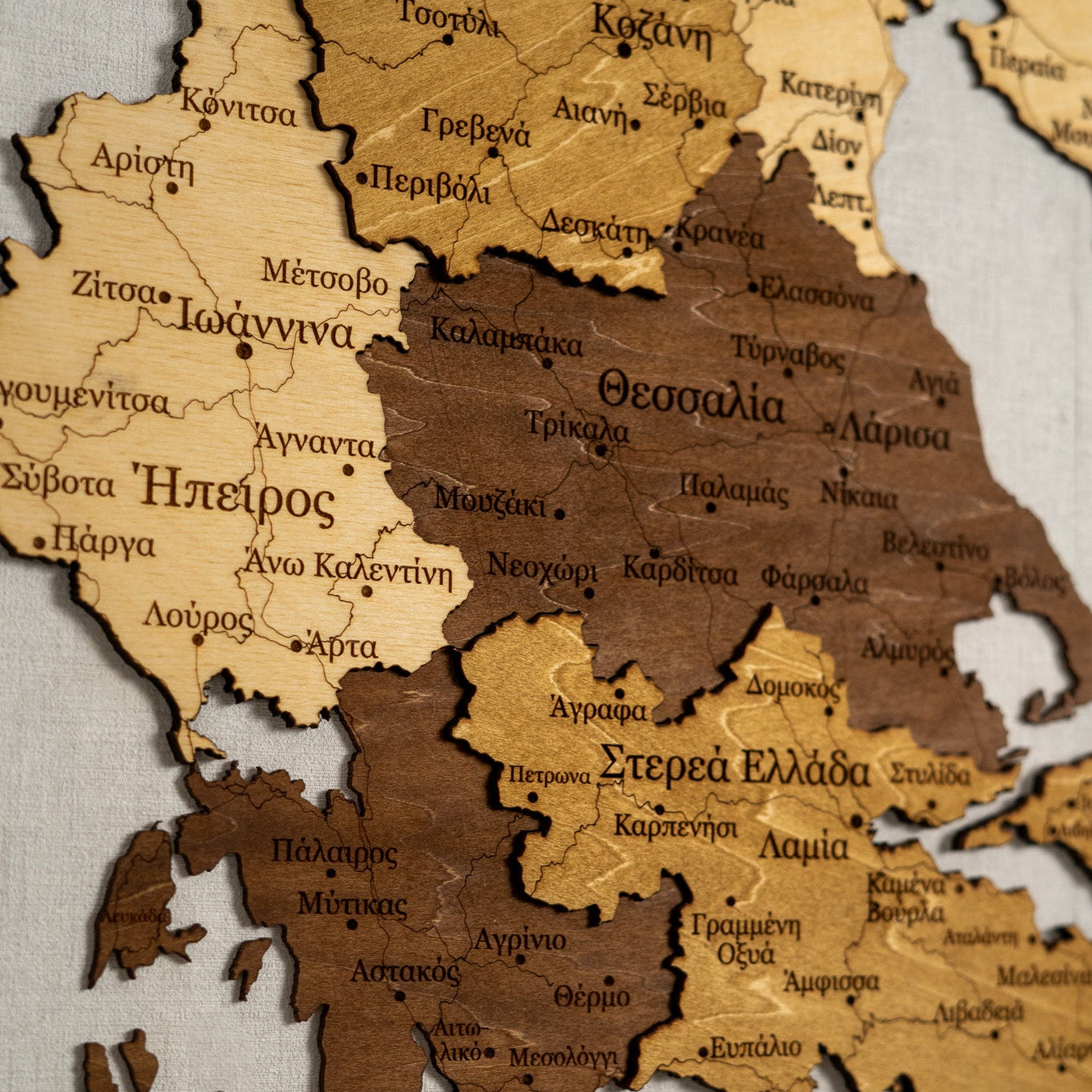 Wooden map of Greece with Greek text on a light background