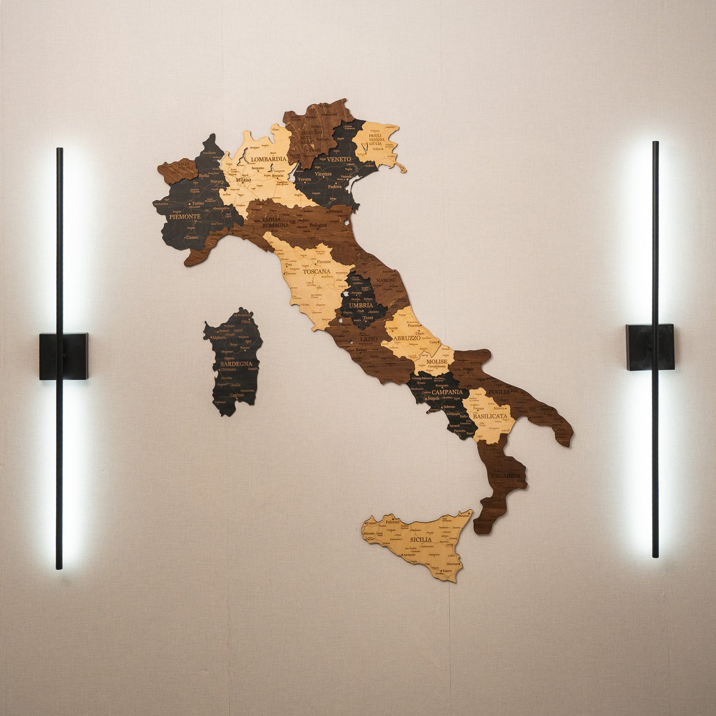 Wooden map of Italy on a wall with two lights on either side.