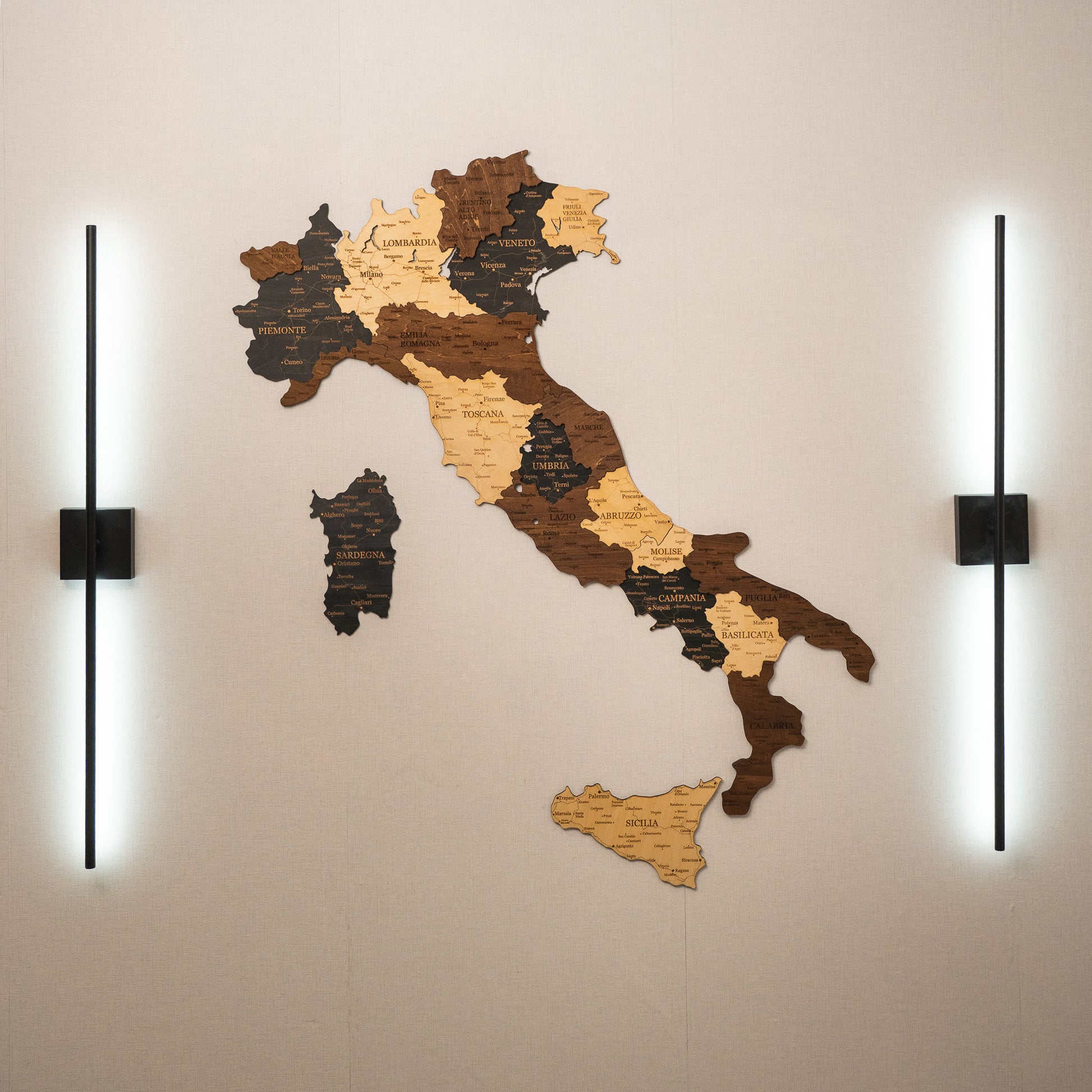 Wooden map of Italy on a wall with two lights on either side.