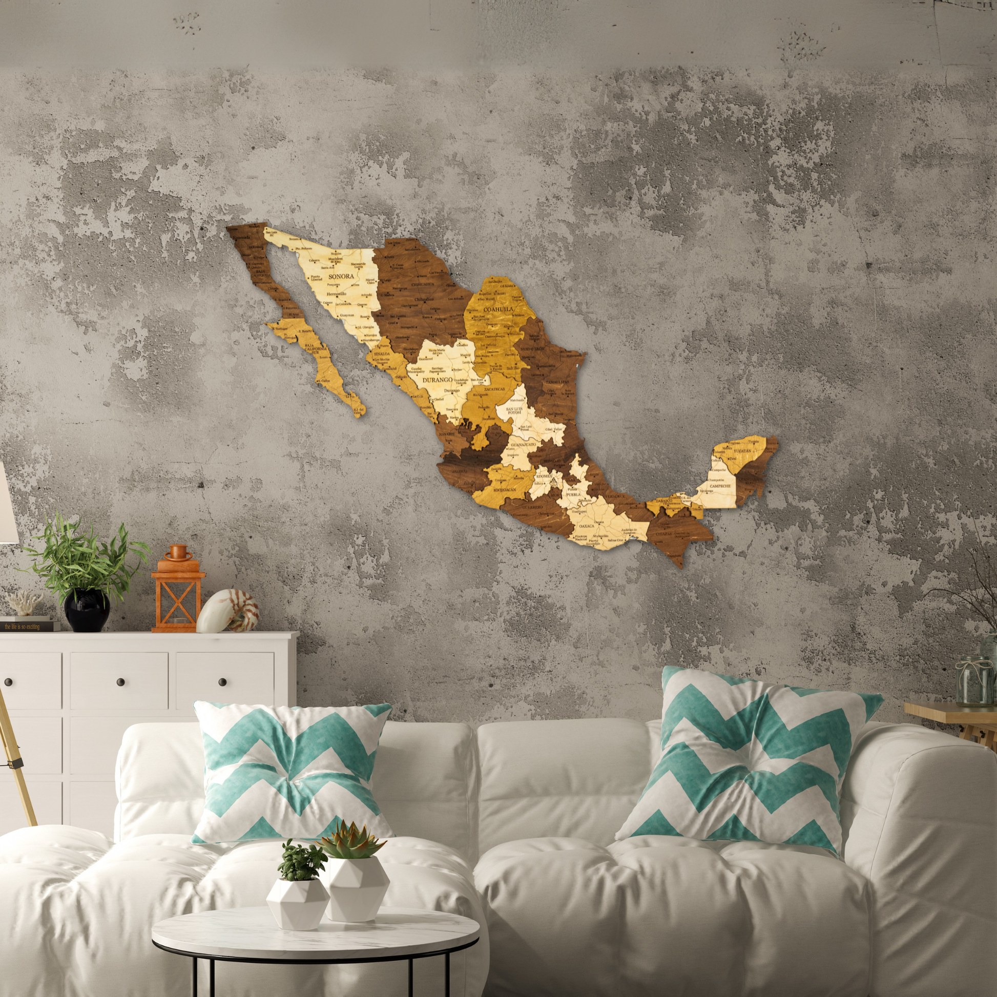 Wooden wall art of Mexico on a textured gray wall above a white sofa with decorative pillows.